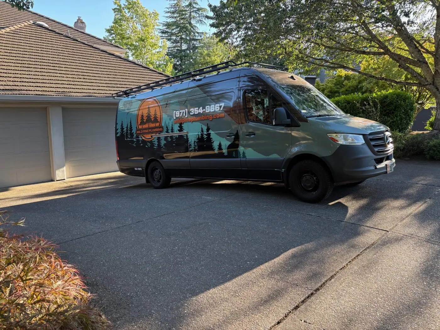 Wild Pine Plumbing wrapped Mercedes Sprinter service van on a residential driveway in Portland, Oregon