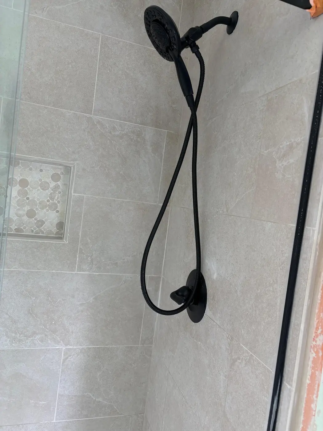 Custom tile shower with matte black rainfall head and handheld wand installed by Wild Pine Plumbing in Portland, Oregon